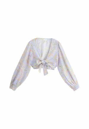Primer plano de los labios y el hombro de una mujer que lleva una blusa lavanda con un patrón floral tropical detallado en tonos suaves.