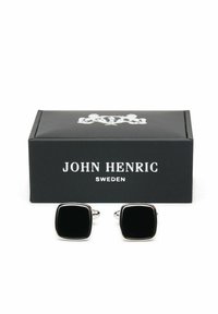 Svarta fyrkantiga manschettknappar med silverdetaljer, visade i en svart låda märkt "JOHN HENRIC SWEDEN." Slät yta och polerad finish.