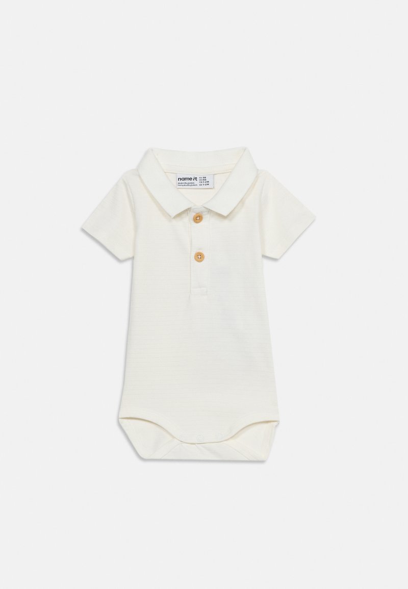 Σώμα μωρού σε κρεμ χρώμα με κοντά μανίκια, γιακά, δύο ξύλινα κουμπιά μπροστά και κούμπωμα με κουμπιά στο κάτω μέρος.