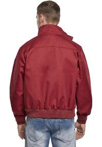 Veste légère rouge avec col montant, poignets et taille côtelés, et une finition lisse. La vue arrière montre un design simple et des coutures.