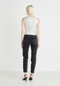 Sølv, tettsittende tank topp med en skinnende paljettstruktur, kombinert med svarte, høy midje jeans. Strappy svarte hæler med hvite aksenter.