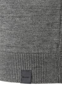 Graues gestricktes Material mit geripptem Saum und kleinem schwarzen rechteckigen Etikett, das auf der unteren Mitte mit "MARKZ" genäht ist.