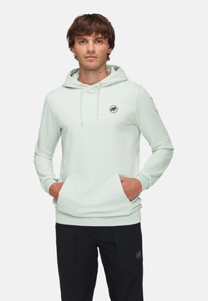Light green hoodie with long sleeves, drawstring hood, front pouch pocket, and a small black logo on the chest. Paired with black pants.