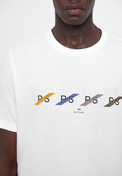 Biała bawełniana koszulka z grafiką kolorowych liter "PS" ułożonych po skos w żółtym, niebieskim, fioletowym i zielonym kolorze.