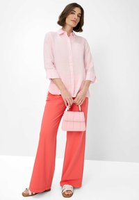 Light pink linen shirt with button closure, coral wide-leg pants, and a small pink handbag with quilted pattern and silver hardware.