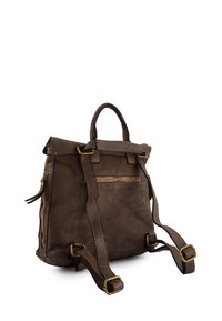 Brown leather backpack with a fold-over top, adjustable straps, and a front zip pocket. Features brass hardware and textured surface.