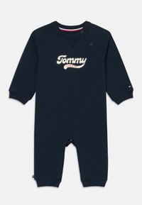 Jūras zila kokvilnas zīdaiņu romperis ar garām piedurknēm, ar spiedpogām uz pleca un izšūtu "Tommy Class of 1985" uz priekšpuses.