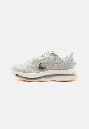 Világosszürke Nike Air Max cipő hálós felsőrésszel, fémes ezüst logóval, átlátszó légpárnás talprésszel és világos bézs külső talppal, oldalsó nézet.