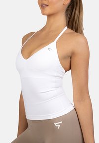 Biała sportowa koszulka na ramiączkach z głębokim dekoltem w kształcie litery V i cienkimi ramiączkami, z delikatnymi szarymi akcentami logo oraz dopasowanym krojem zapewniającym komfort i wsparcie.