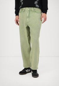 Light green denim pants with a relaxed fit, featuring a button and zipper closure, two front pockets, and horizontal stitching detail.