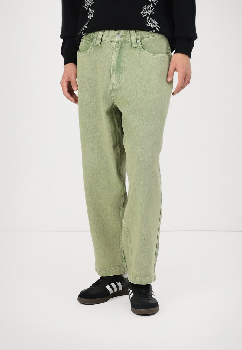 Light green denim pants with a relaxed fit, featuring a button and zipper closure, two front pockets, and horizontal stitching detail.