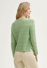 Grüner gestrickter Pullover mit einem strukturierten, gestreiften Muster. Lange Ärmel, runder Halsausschnitt und ein leichter Seitenschlitz am Saum.