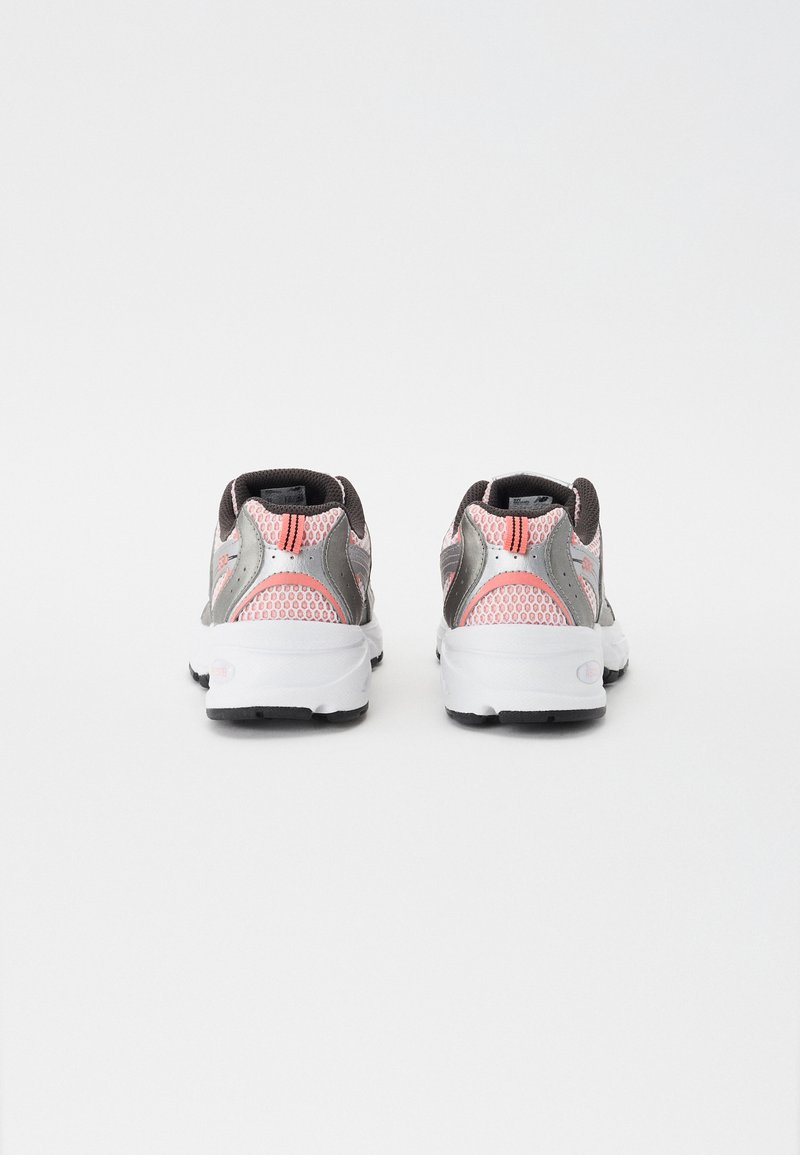 Graue Sportschuhe mit rosa Mesh-Akzenten, ausgestattet mit einer weißen Sohle und einer schwarzen Außensohle. Das Design umfasst gepolsterte Fersen und reflektierende Details.