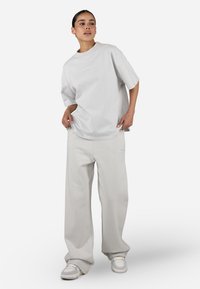 Light gray oversized t-shirt with a round neckline and short sleeves, paired with matching wide-leg sweatpants made of soft material.