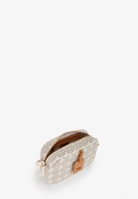 Borsa cosmetica bianca con un motivo ornato beige, chiusura a doppia zip e un'etichetta in pelle marrone. Superficie texturizzata con interno color sabbia.