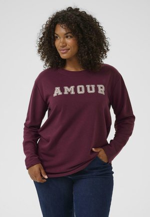 Maroon long-sleeve sweatshirt featuring the word "AMOUR" in light-colored lettering. Made from a soft, textured fabric. Casual fit.