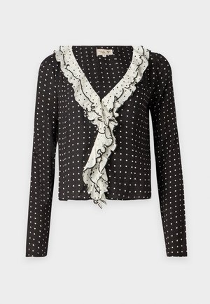 Musta pitkähihainen paita, jossa on valkoisia poolopisteitä ja valkoisella reunustettu röyhelö V-kaula-aukko, valmistettu pehmeästä, teksturoidusta kankaasta.