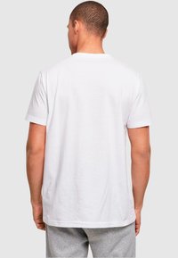 White cotton t-shirt with short sleeves, standard crew neckline, and a relaxed fit. Smooth texture, no visible patterns or logos.