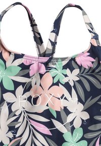 Blommig baddräkt med marinblå bakgrund och rosa, gröna och beige blommor, justerbara remmar och vitt "ROXY"-logotyp med cirkelformad design.