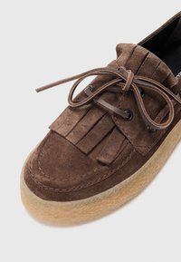 Brune semskede sko med frynser, rund tå og snøringer. Har en struktureret, naturfarget såle, som fremhever et uformelt design.