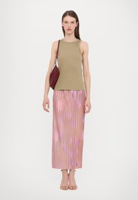 Beige ribbad linne kombinerat med en rosa, veckad kjol med blommönster. Modellen håller en vinröd handväska och bär remsandaler.