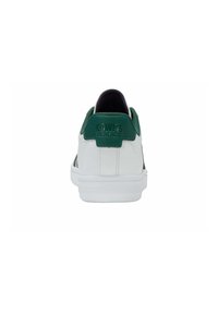 Zapatilla blanca con acentos verdes, que presenta un talón texturizado y un logotipo en la parte posterior. Suela de goma y parte superior de cuero suave.