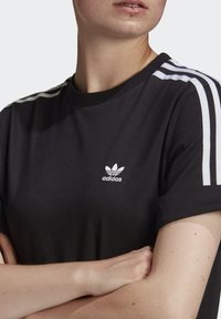 Czarny bawełniany t-shirt z białym logo Adidas i trzema białymi paskami na rękawach; okrągły dekolt, krótkie rękawy i miękka tekstura.