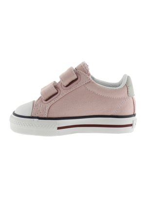 Zapatilla de lona rosa con dos correas de Velcro, puntera de goma blanca y suela texturizada. Presenta una línea roja contrastante a lo largo de la base.