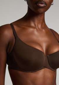 Bruine onderwired bra met een gladde textuur en naadloze cups. Verstelbare banden en minimalistisch ontwerp zonder decoratieve accenten of patronen.