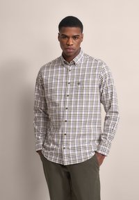 Beige Hemd mit grünem und blauen Karomuster, ausgestattet mit einer Brusttasche und braunen Knöpfen. Baumwollstoff mit glatter Textur.