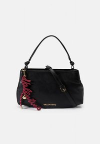 Svart lærveske med strukturet design, kort håndtak og avtakbar skulderstropp. Har gulllogo og rød sjarmdetalj.