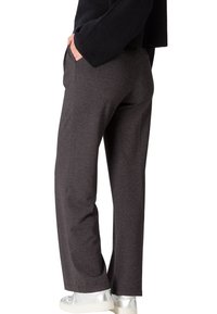 Pantalons gris à jambe large en tissu doux et texturé. Dotés de poches latérales et d'une coupe décontractée, associés à des baskets argentées.