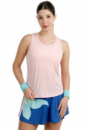 Vrouw met een mouwloze roze tanktop, een blauwe rok met een grote lichtblauwe bloemenprint en bijpassende turquoise polsbandjes.