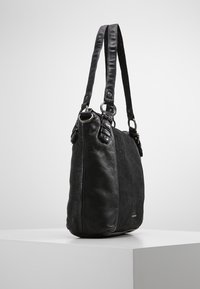 Černá kožená kabelka s texturovaným povrchem, vybavená dvojitými úchyty, kruhovými kovovými ozdobami a elegantním, prostorným designem.