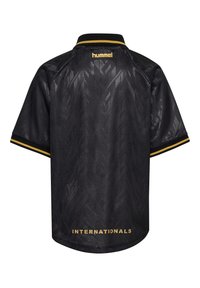 Schwarzes Sporttrikot mit kurzen Ärmeln, dezenten geometrischen Mustern, goldenem „hummel“-Logo am oberen Rücken und dem Schriftzug „INTERNATIONALS“ nahe am Saum.