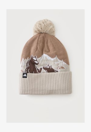 Beige strikket hue med pompon, foldet kant og brun bjørn samt bjerglandskabsmønster.