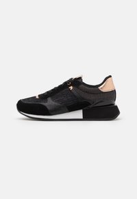 Scarpa sportiva nera con pannelli in rete e suede, dettagli in oro rosa, lacci piatti e un tacco spesso nero. Suola in gomma per una buona aderenza.