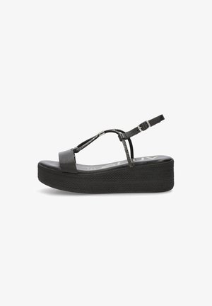 Sandalias de plataforma negras con suela de goma texturizada, diseño de tira en T y hebilla ajustable en el tobillo. Superficie superior lisa con mínimos acentos.