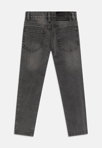 Jeans de color gris oscuro con corte slim, que cuentan con dos bolsillos traseros, una textura suave y una etiqueta de cuero negro con logo en la cinturilla.