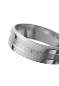 Hopea metallinen rengas kiiltävällä pinnalla, jossa on kaiverrettu teksti "DANIEL WELLINGTON" ja teksturoitu bändimuotoilu.