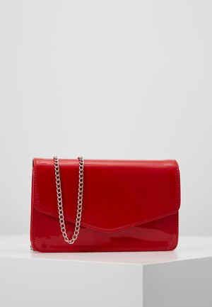 Blank rød rektangulær clutch taske med en sølvkæde, placeret på en hvid platform mod en ensartet lysegrå baggrund.