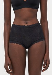 High-waisted black lace panties with floral pattern, scalloped edges, and smooth texture. Designed for comfort and style.