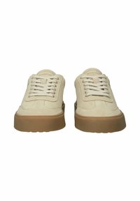 Pari beigeä mokkanahkaisia tennareita, joissa valkoiset nauhat ja paksut ruskeat kumipohjat, nähtynä edestä valkoisella taustalla.