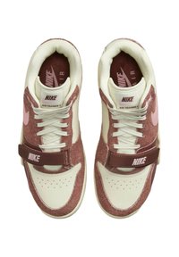 Nike Air Trainer 1 kengät, joissa on kerma värinen nahkapohja, vaaleanpunaiset mokka-korostukset ja ruskea hihna logolla. Rakenteelliset pinnat ja rei'itykset.