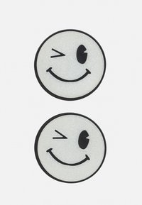 Dois ímans de rosto sorridente circulares com uma textura brilhante. Um apresenta uma piscadela, enquanto o outro exibe um sorriso padrão. Acentos pretos contornam ambos.