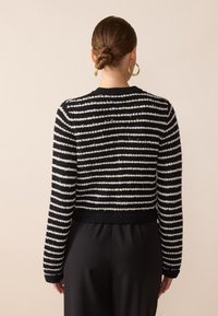 Randig tröja i svart och vitt med en texturerad stickad design, rundad hals och långa ärmar. Kortad passform med ribbade mudd och nederkant.