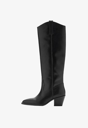 Bottes en cuir noir, hautes, avec un bout carré et un talon de hauteur moyenne. Présente des détails de couture et une languette sur le côté pour un enfilage facile.