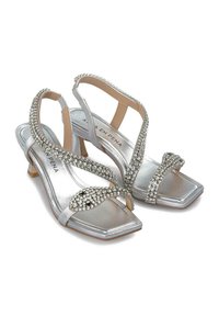 Silverfärgade sandaler med klack och fyrkantig tå, eleganta remmar prydda med rhinstenar. Har en låg blockklack och en slät metallisk finish.