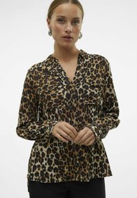 Hedvábná blůza s leopardím vzorem a límcem, dvěma náprsními kapsami, dlouhými rukávy a knoflíkovým zapínáním. Vyrobena z měkkého materiálu s volným střihem.