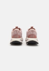 Lyserosa Nike joggesko med teksturert strikkoverdel, polstret krage og kontrastfarget svart såle, med merkevaren sitt logo på hælen.